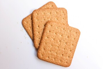 three square shaped biscuit stacked on white background, top view, selective focus