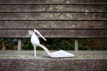 Single bridal shoe seen in profile and placed on ruined wood outdoors