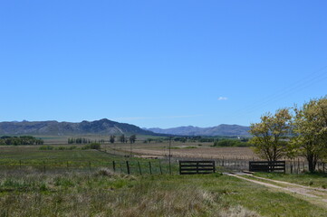 Fototapeta na wymiar Entrada a campo con sierras de fondo con la tranquera abierta 