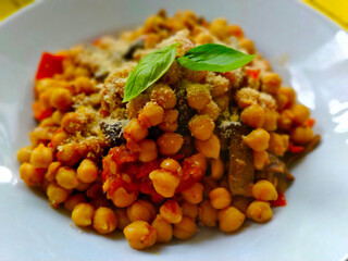 Detail view on delicious home-made dish made of chickpea and mushrooms. There are few basil leaves in the top.