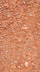 Detail view of road structure made of orange clay and small stones.
