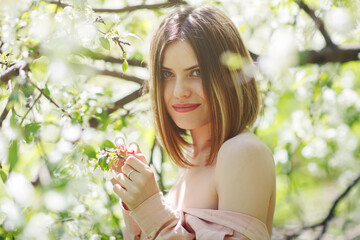 Portrait of a beautiful girl in the garden of blooming apple trees