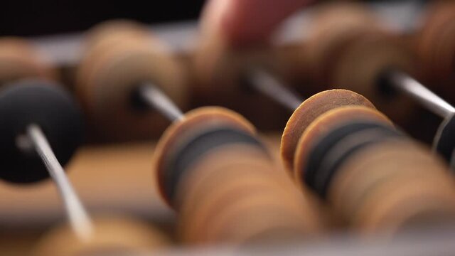 Macro shot of a male finger counting using old wooden abacus.Shallow depth of field.
