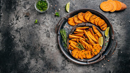 Metel tray with sweet potato fries with lime and herbs on dark background. Long banner format. top view