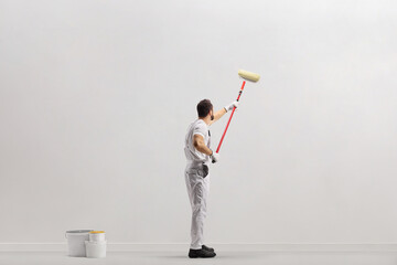 Painter using a paint roller and painting a wall