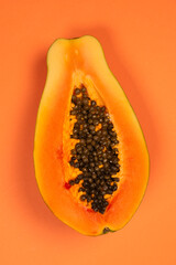 Papaya fruit on a orange background. Half papaya.