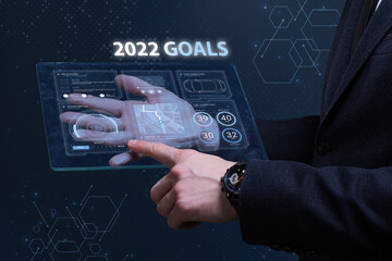 Business, Technology, Internet and network concept. Financial Graph. Stock Market chart. Young businessman working on a virtual screen of the future and sees the inscription: 2022 goals