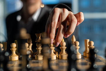 Business woman in a suit plays chess. Close-up of a female hand on a pawn