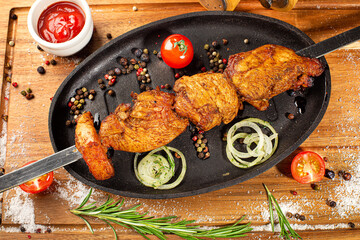 Grilled lamb skewers with spices and vegetables on a pan