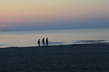Troje ludzi na plaży po zachodzie słońca, spokój, Bałtyk