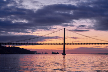 Fototapeta na wymiar Beautiful landscape with suspension 25 April bridge bridge over the Tagus river in Lisbon at sunset.