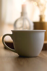 Cup of warm drink, lit candles and flowers on a table. Hygge at home. Selective focus.