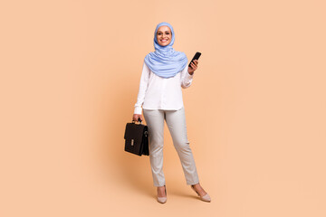 Full size photo of young arabic trend ceo lady with bag wear headscarf shirt eyewear pants stilettos isolated on peach background