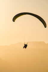 Vol en parapente en montagne en fin de journée durant le coucher du soleil