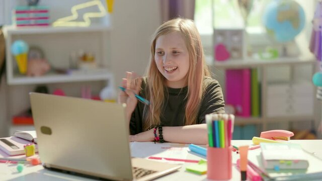 tired modern girl in grey shirt with laptop, headphones and workbook homeschooling and stretching at home in sunny day.
