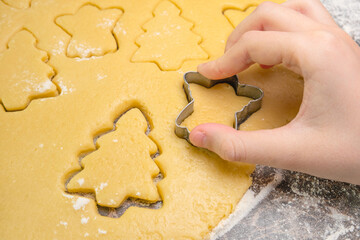 Kids hand with form of christmas cookies for children, making gingerbread in form of man. New year...