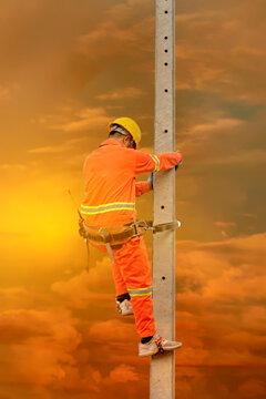 An electrician in a safety suit is climbing a light pole To go up and check availability Of the electrical system requesting a light pole sent to the public house