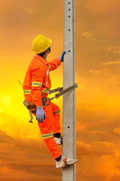 An electrician in a safety suit is climbing a light pole To go up and check availability Of the electrical system requesting a light pole sent to the public house