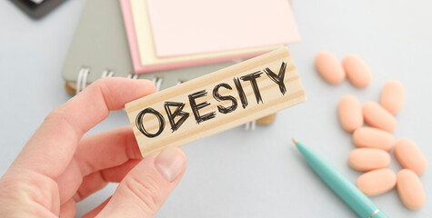 Obesity Word on wooden block, medical concept, hands