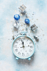 Christmas, New Year composition on sky blue background with modern alarm clock and silver color Christmas decorations - stars, confetti, balls and gift boxes, top view, flat lay