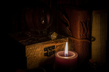 Metallic d20 on a wooden box in candlelight