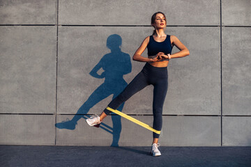 sporty woman doing exercises with resistance band, fitness woman doing leg exercises with yellow fitness rubber band