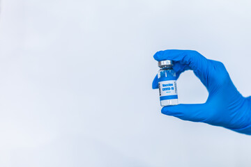 doctor hand wears medical glove holding vaccine bottle on a white background. copy space