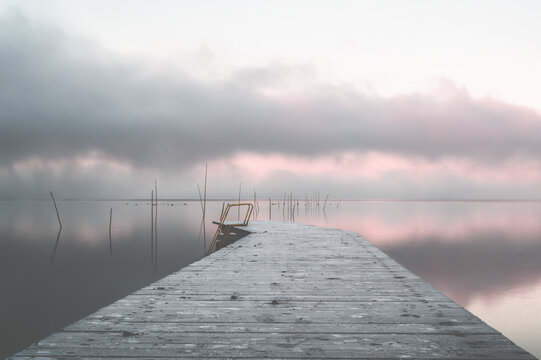 Light wooden dock on still sea under clouds