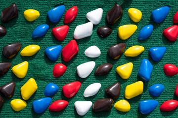 texture with multi-colored stones. objects of different colors on a green background. multicolored pebbles