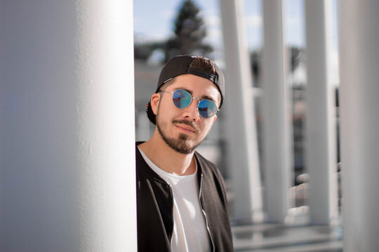 Man wearing sunglasses and cap beside light posts