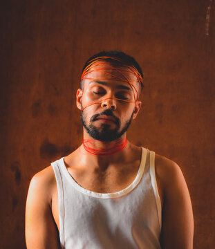 Portrait of man with head wrapped by red thread