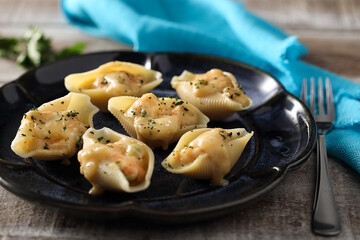 Prato com conchiglione recheado sobre mesa com guardanapo azul