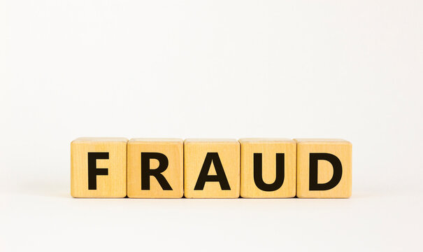 Fraud symbol. The concept word 'fraud' on wooden cubes on a beautiful white table. White background. Business and fraud concept.