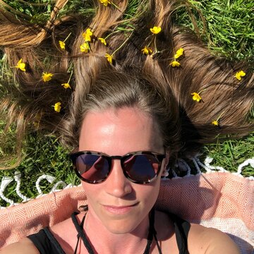 Woman in black sunglasses lying on grass