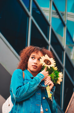 Woman in blue zip up jacket holding sunflower