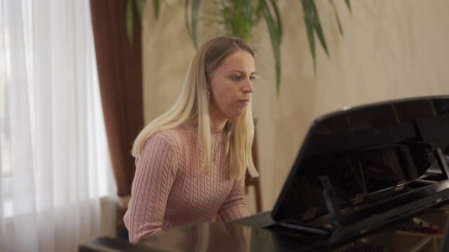 young attractive girl with long blond hair and attractive blue eyes enjoys playing the piano
