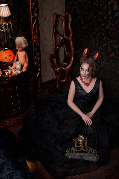 Woman in long dark dress with devil make-up in indoor
