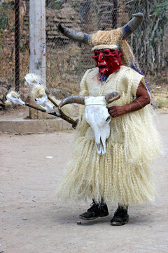 Woman wearing a white dress and horns with devil's mask standing outdoor