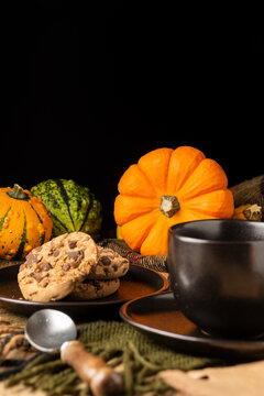 Yellow and green pumpkins beside plate of biscuits on brown wooden table