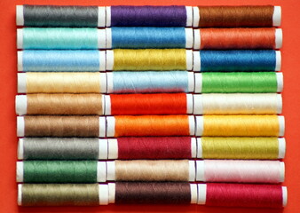 rows of spools of multicolored sewing threads are located throughout the photo