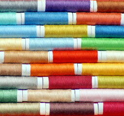 macro shot of rows of spools of multicolored sewing thread, laid alternately, with an offset. photo square