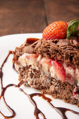 Chocolate cake, a tasty slice of chocolate cake with strawberries on a white plate on rustic wood, abstract background, selective focus.
