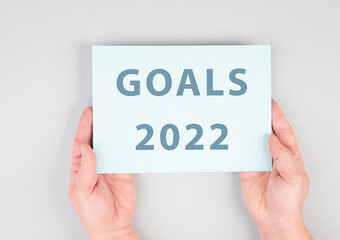 Goals 2022 is standing on a paper, hands are hold in the message, planning new achievements for the new year