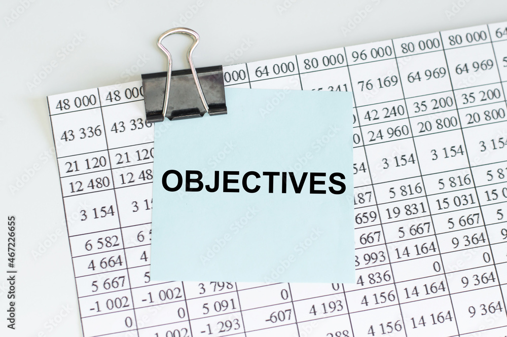 Poster text objectives on a blue card on the background of a sheet with numbers on the table