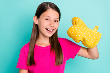 Portrait of attractive cheerful schoolkid showing thumbup with hand glove isolated over bright teal...