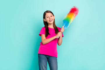 Portrait of attractive cheerful schoolchild wiping dust having fun cozy home isolated over bright teal turquoise color background