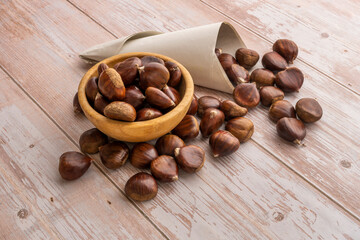 Chestnut cornet and wooden bowl with chestnuts on a light wooden table