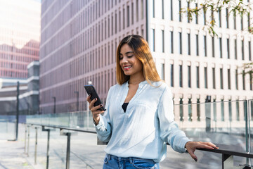 Young professional female architect working on new project, using mobile phone while smiling. Business concept