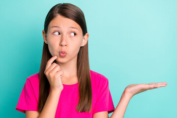 Photo of dreamy minded curious girl hold hand empty space look imagine object isolated on teal...