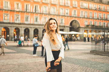Young caucasian woman portrait with a white blouse and a black skirt at Madrid's Plaza Mayor, Spain.